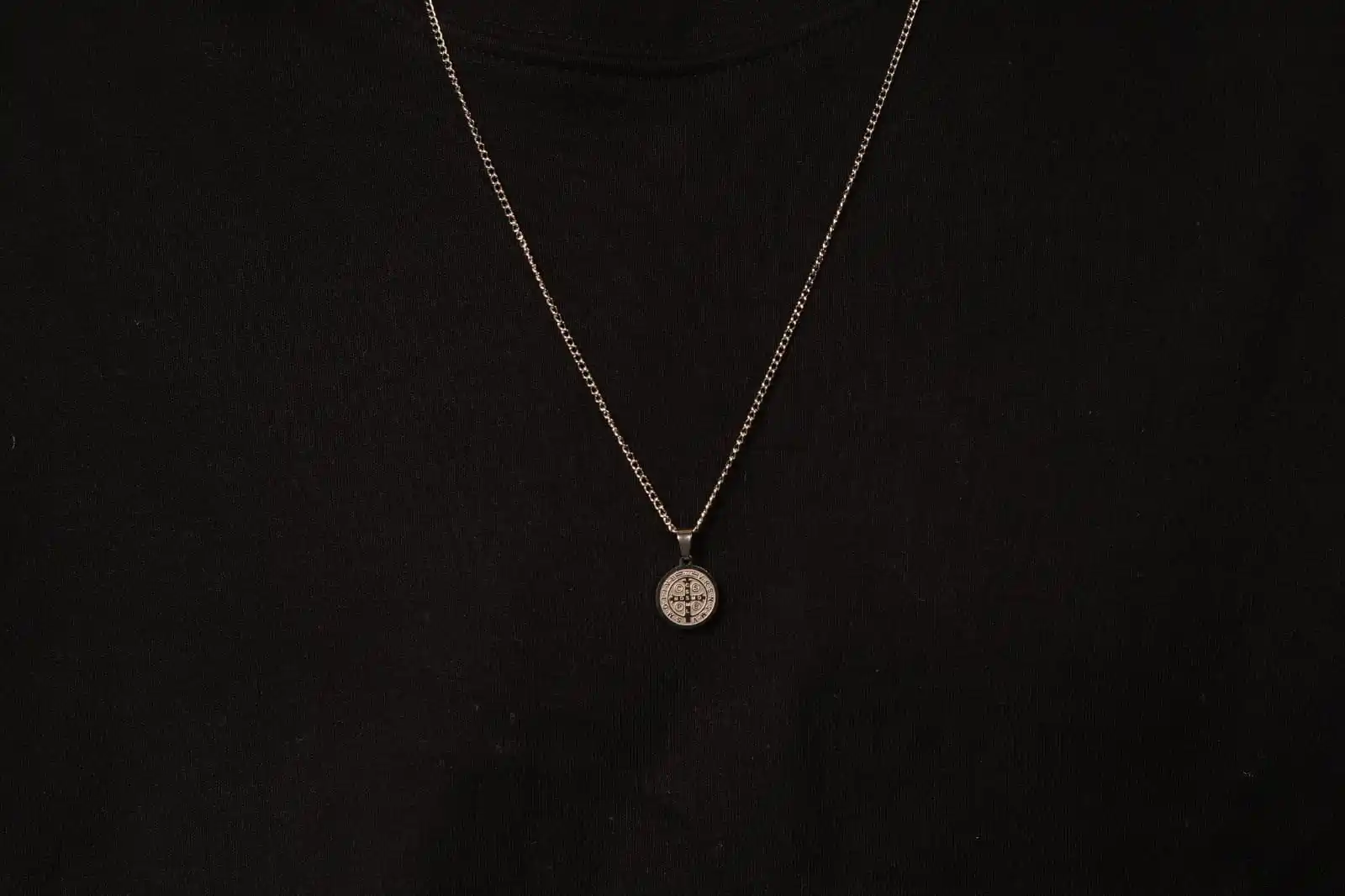 Material da corrente e do pingente: Aço inoxidável Estilo da corrente: Veneziana Espessura da corrente: Aproximadamente 1,5 mm Comprimento da corrente: Médio/longo (estimado entre 60 a 70 cm) Pingente: Medalha de São Bento, com gravações visíveis em alto relevo Cor: Prata envelhecida